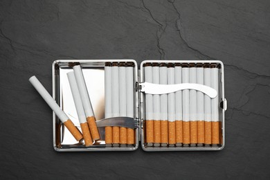 Stylish case with cigarettes on black table, top view