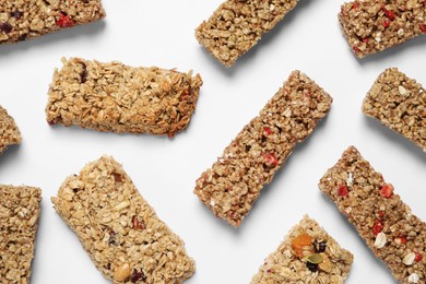 Tasty granola bars on white background, flat lay