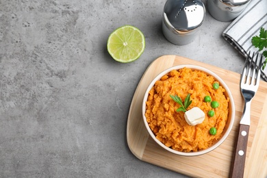 Bowl of sweet potato puree served on grey table, top view. Space for text