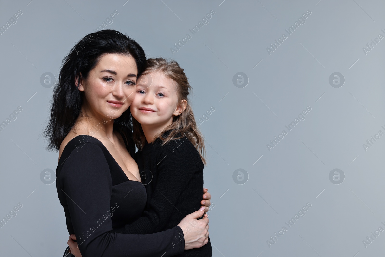 Photo of Beautiful mother hugging with little daughter on grey background. Space for text