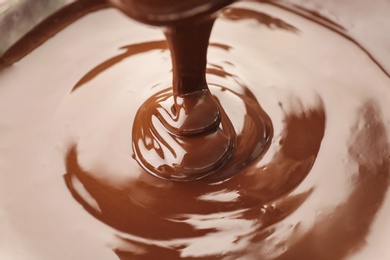 Photo of Pouring delicious melted milk chocolate, closeup