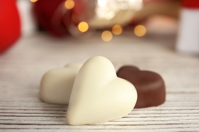 Photo of Tasty heart shaped chocolate candies on white wooden table, closeup. Valentine's day celebration