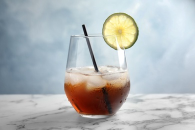 Photo of Glass of cocktail with cola, ice and cut lime on table