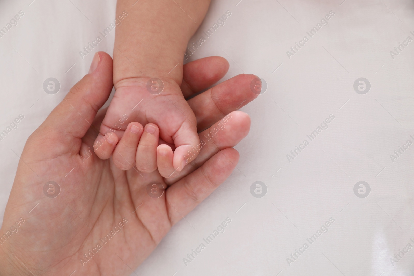 Photo of Mother with her baby on bed, closeup of hands. Space for text