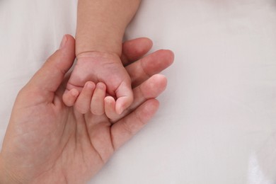 Photo of Mother with her baby on bed, closeup of hands. Space for text