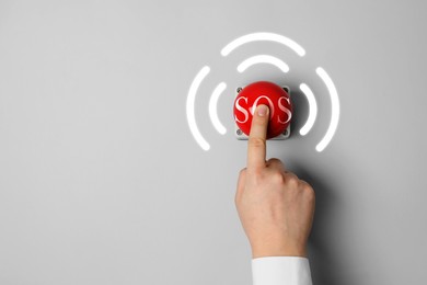 Image of Man pressing red SOS button at white background, closeup