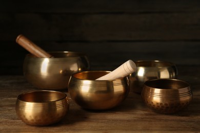 Golden singing bowls with mallets on wooden table