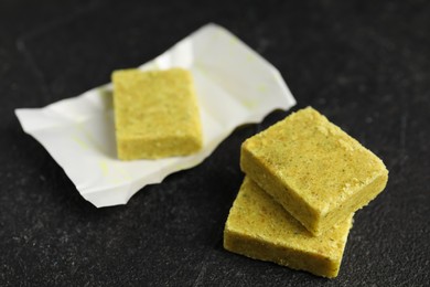 Photo of Aromatic natural bouillon cubes on black table, closeup