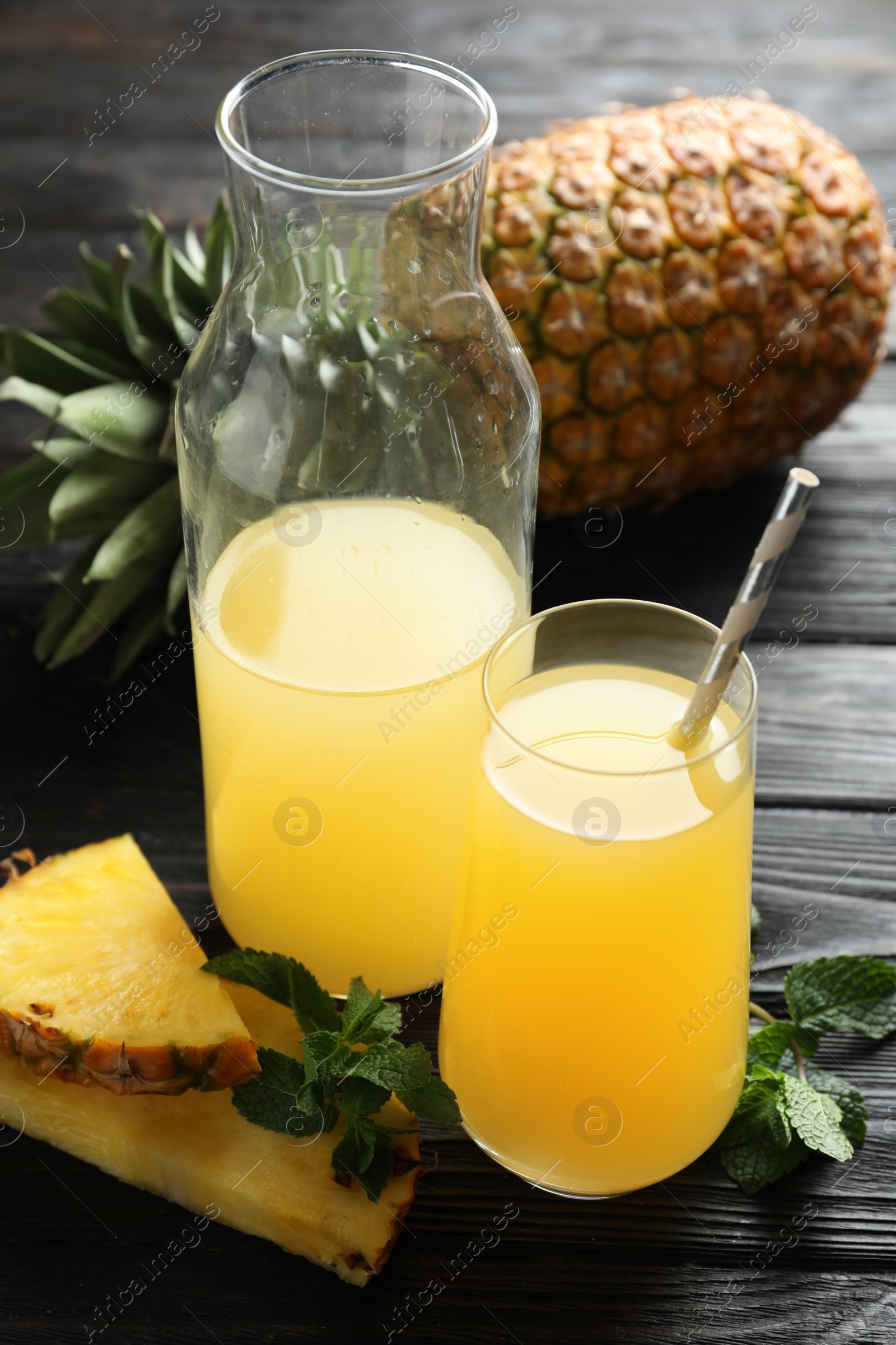 Photo of Delicious fresh pineapple juice on black wooden table