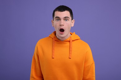 Portrait of surprised man on purple background