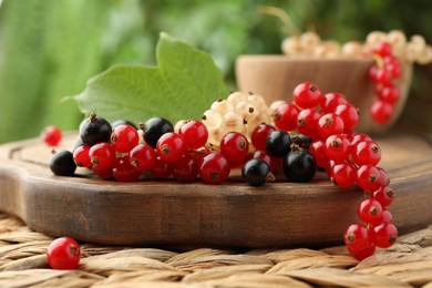 Photo of Different fresh ripe currants and green leaf on table, closeup