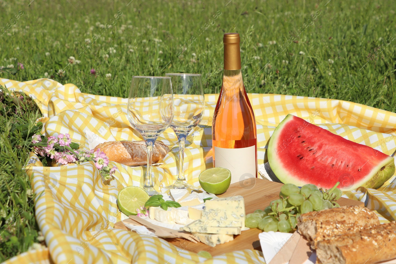 Photo of Picnic blanket with delicious food and wine on green grass outdoors