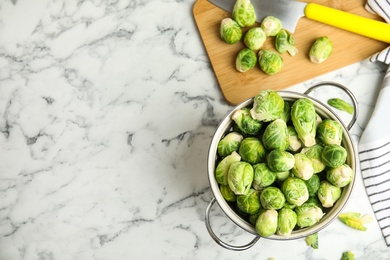 Fresh Brussels sprouts on white marble table, flat lay. Space for text