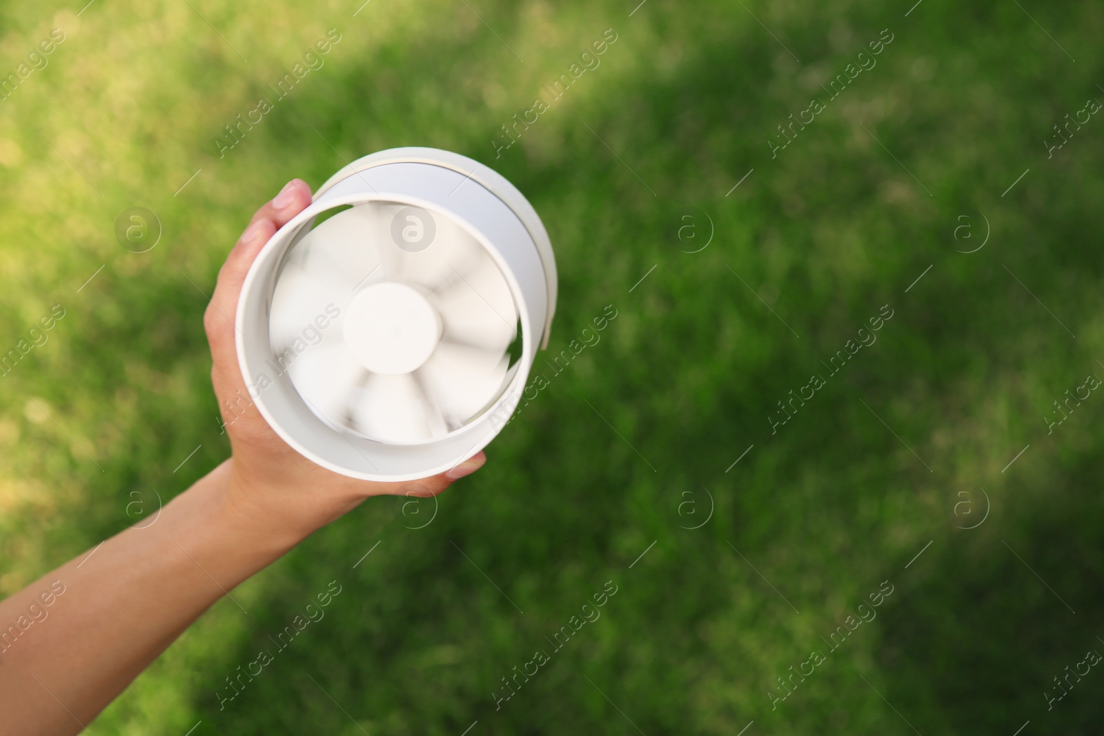 Photo of Woman holding portable fan outdoors on sunny summer day, closeup. Space for text