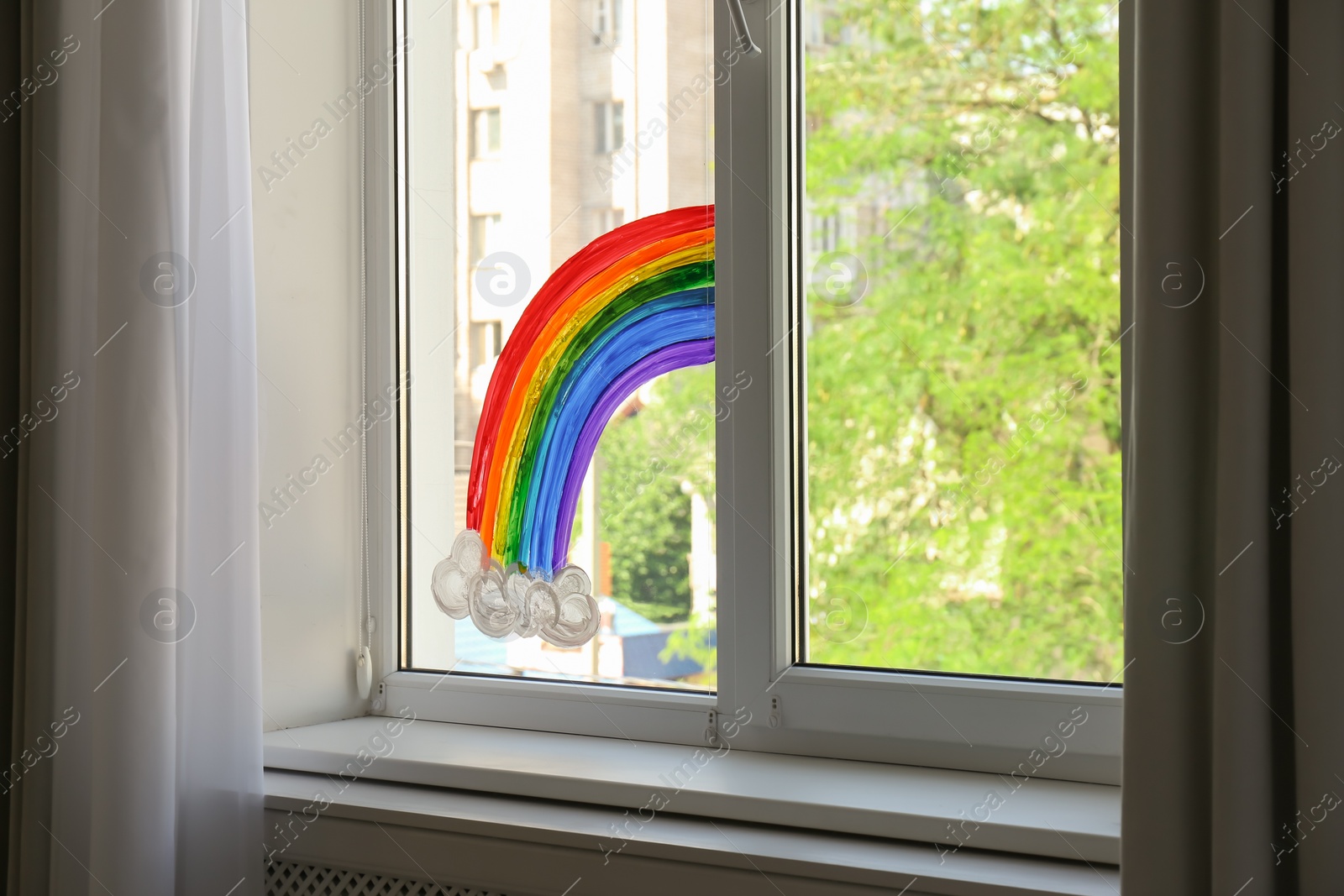 Photo of Picture of rainbow on window glass indoors. Stay at home concept