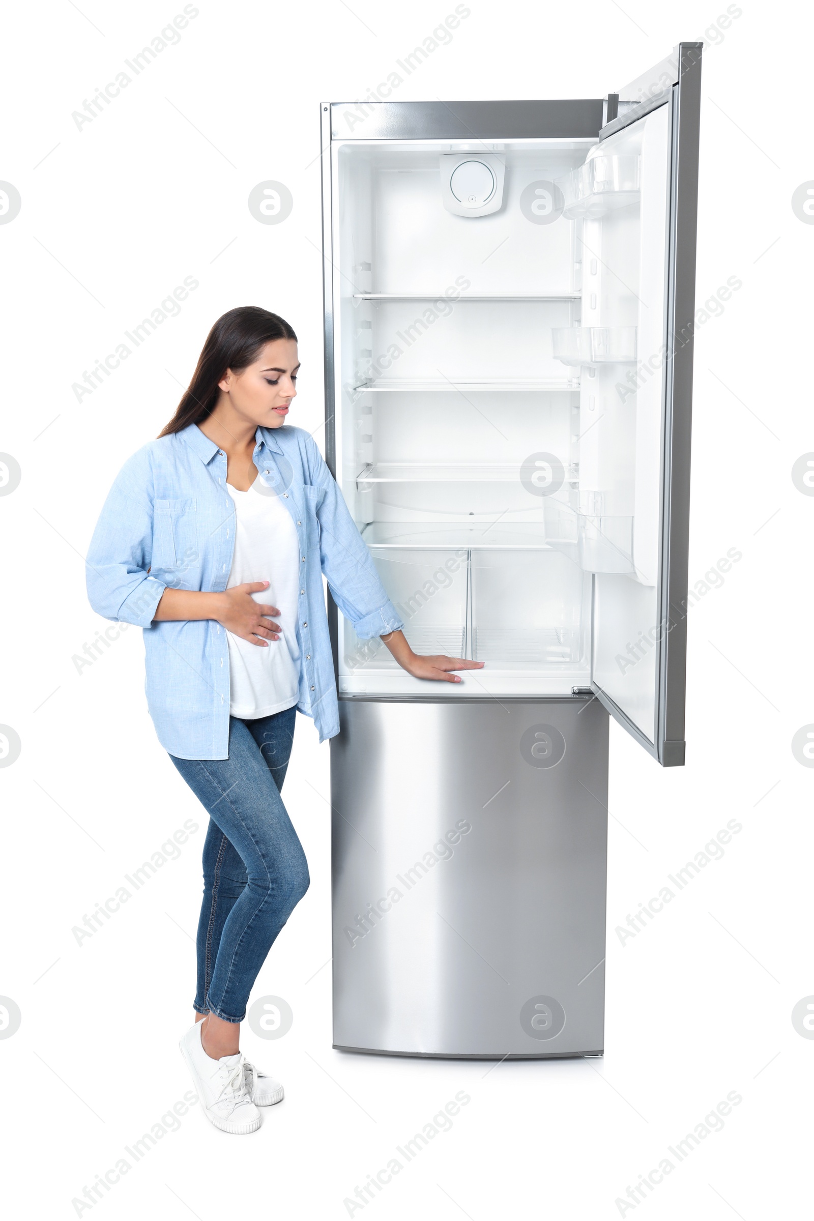 Photo of Hungry woman near empty refrigerator on white background