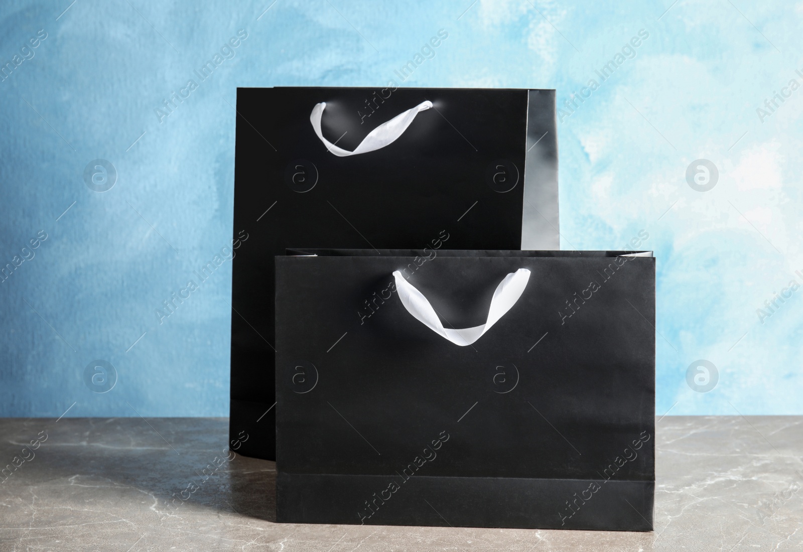 Photo of Paper shopping bags on table against color background. Mock up for design