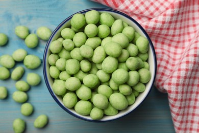 Photo of Tasty wasabi coated peanuts on turquoise wooden table, flat lay