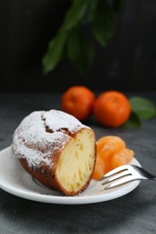 Photo of Piece of delicious homemade yogurt cake with powdered sugar and tangerines on gray table