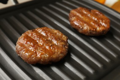 Photo of Delicious hamburger patties on electric grill, closeup