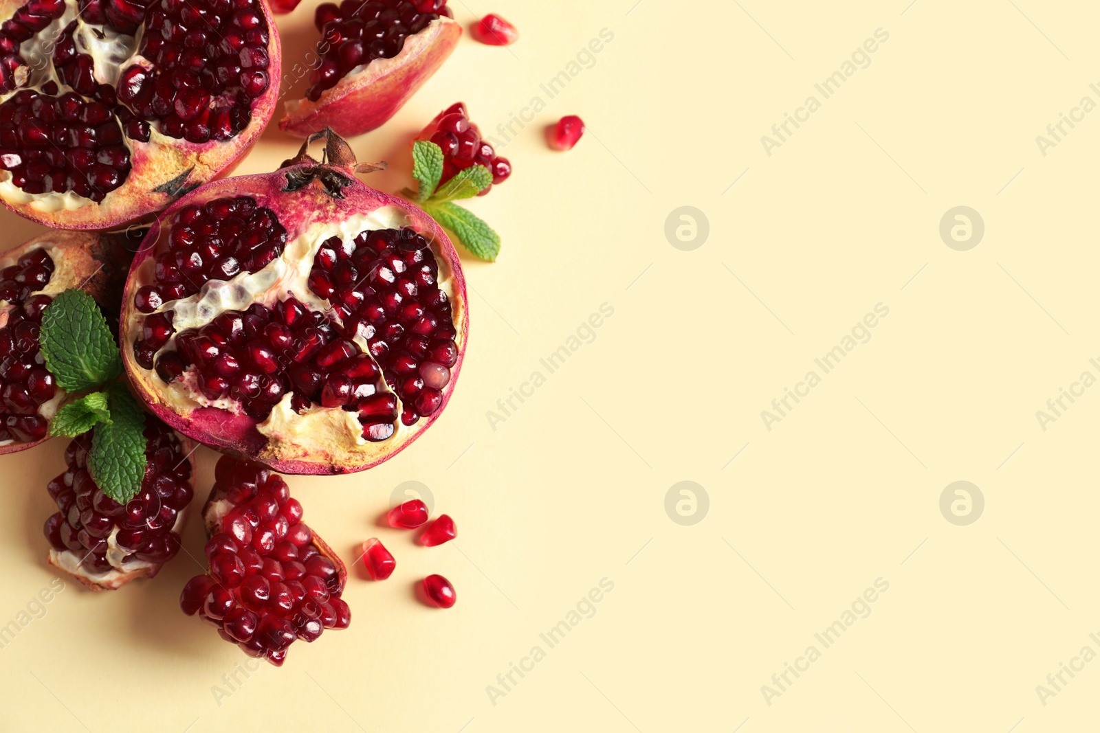 Photo of Ripe pomegranates and seeds on color background, top view with space for text