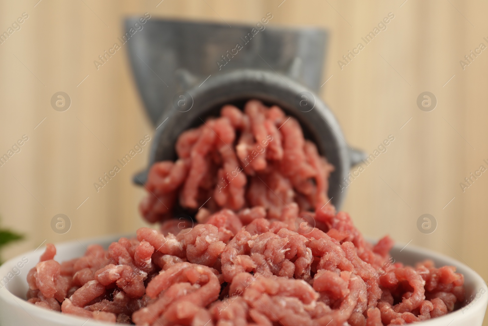 Photo of Mincing beef with manual meat grinder on blurred background, closeup