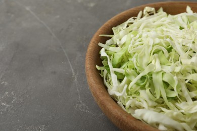 Photo of Chopped cabbage in bowl on grey table, closeup. Space for text
