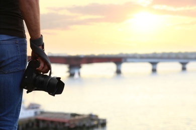 Photographer with professional camera near river, closeup