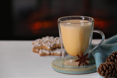 Photo of Tasty eggnog, anise star and cones on white wooden table, closeup. Space for text