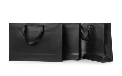 Photo of Paper shopping bags with ribbon handles on white background. Mockup for design