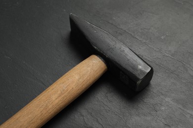 Photo of New hammer on black textured table, closeup. Professional construction tool