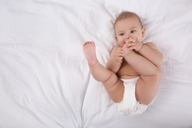 Photo of Cute baby in dry soft diaper on white bed, top view. space for text
