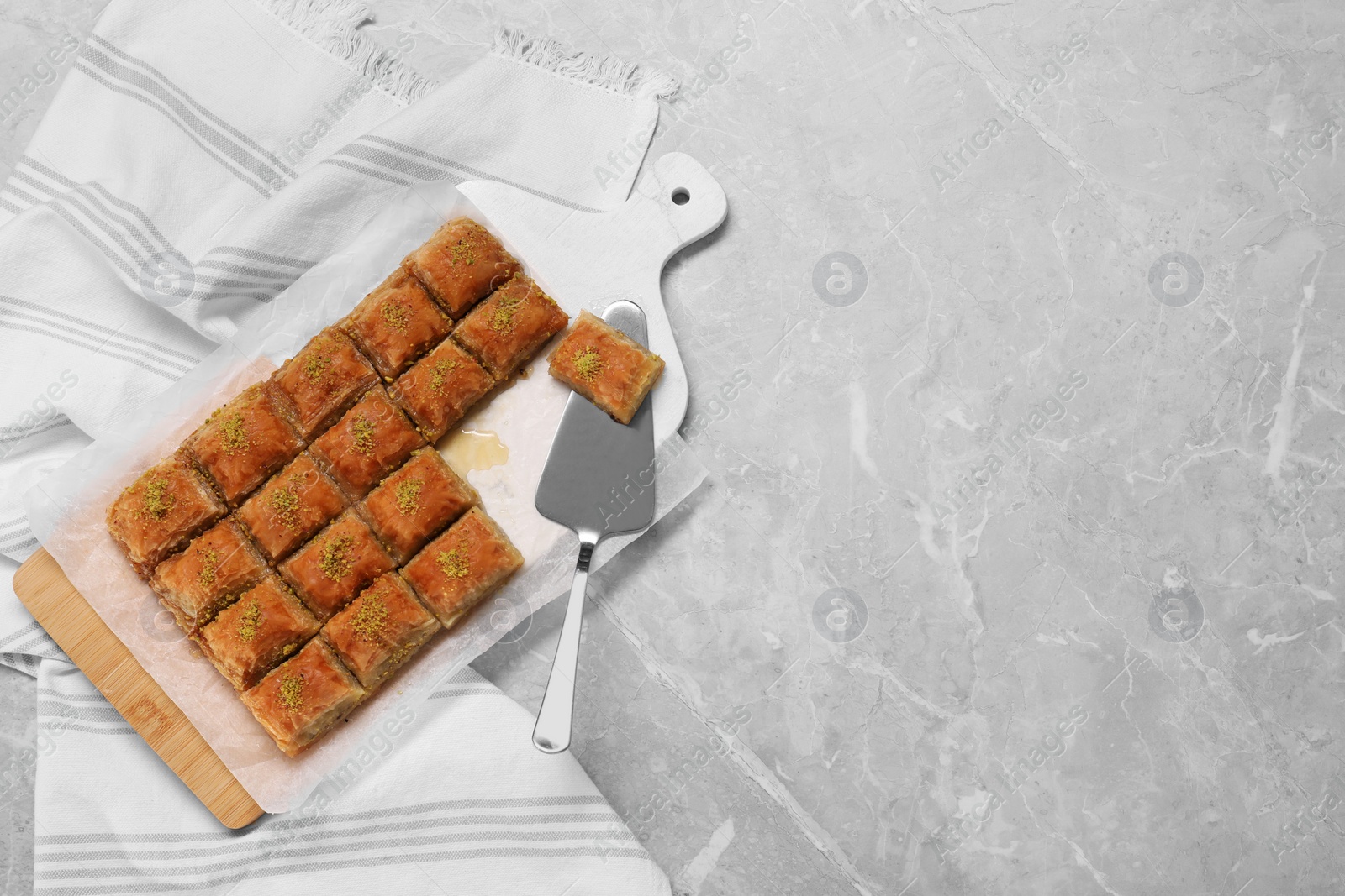 Photo of Delicious sweet baklava and cake server on light grey marble table, top view. Space for text