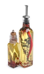 Glass bottles of cooking oil with spices and herbs on white background