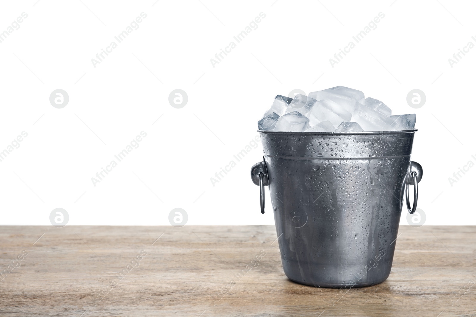 Photo of Metal bucket with ice cubes on wooden table against white background