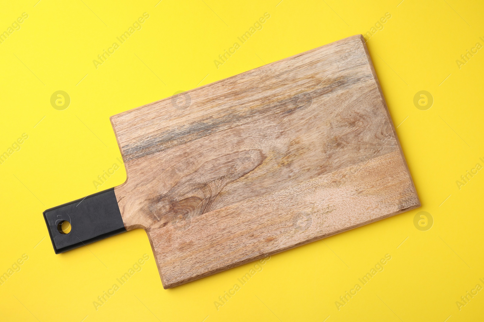 Photo of One wooden board on yellow background, top view