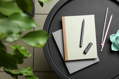 Notebooks, pen, pencils and decor on round table indoors, top view