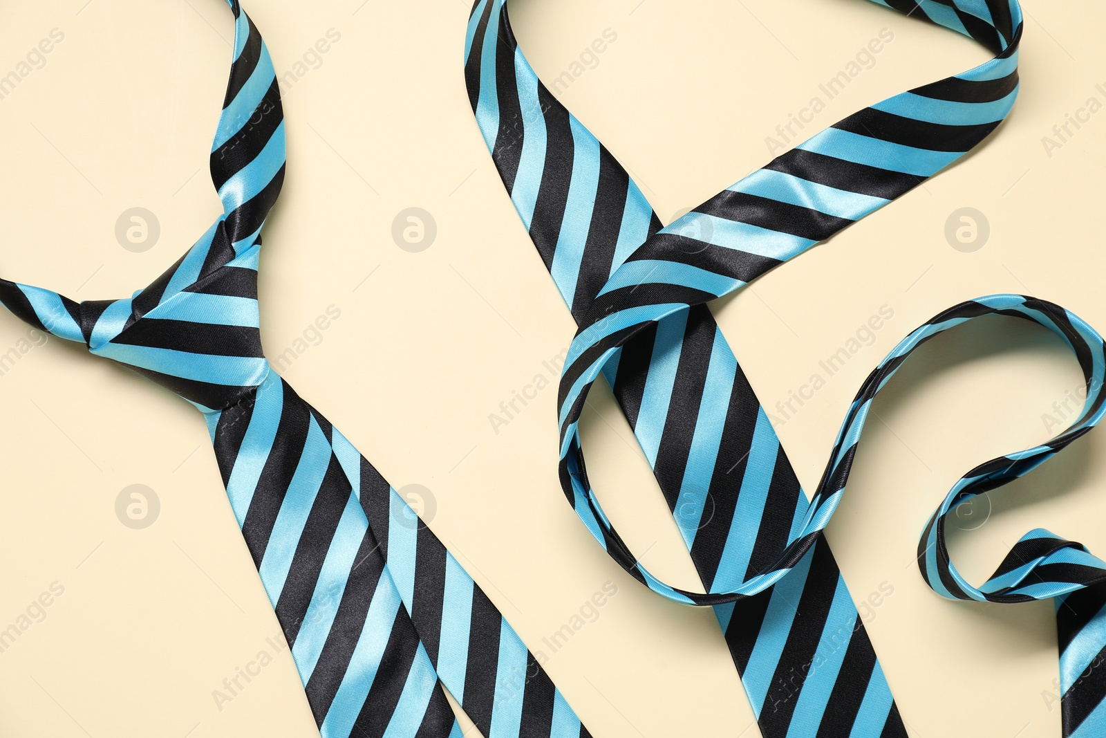 Photo of Striped neckties on beige background, top view