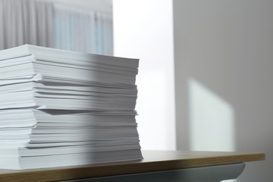 Photo of Stack of paper sheets on wooden table indoors. Space for text