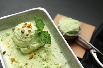 Photo of Container of sweet pistachio ice cream on black table, closeup