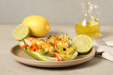 Photo of Baked stuffed zucchinis served with lime on light table, closeup