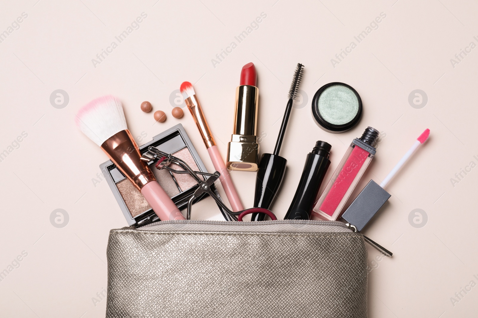 Photo of Cosmetic bag with makeup products and accessories on beige background, flat lay