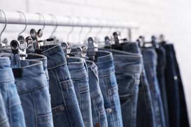 Photo of Rack with stylish jeans on light background, closeup