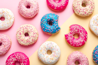 Photo of Delicious glazed doughnuts on color background, top view