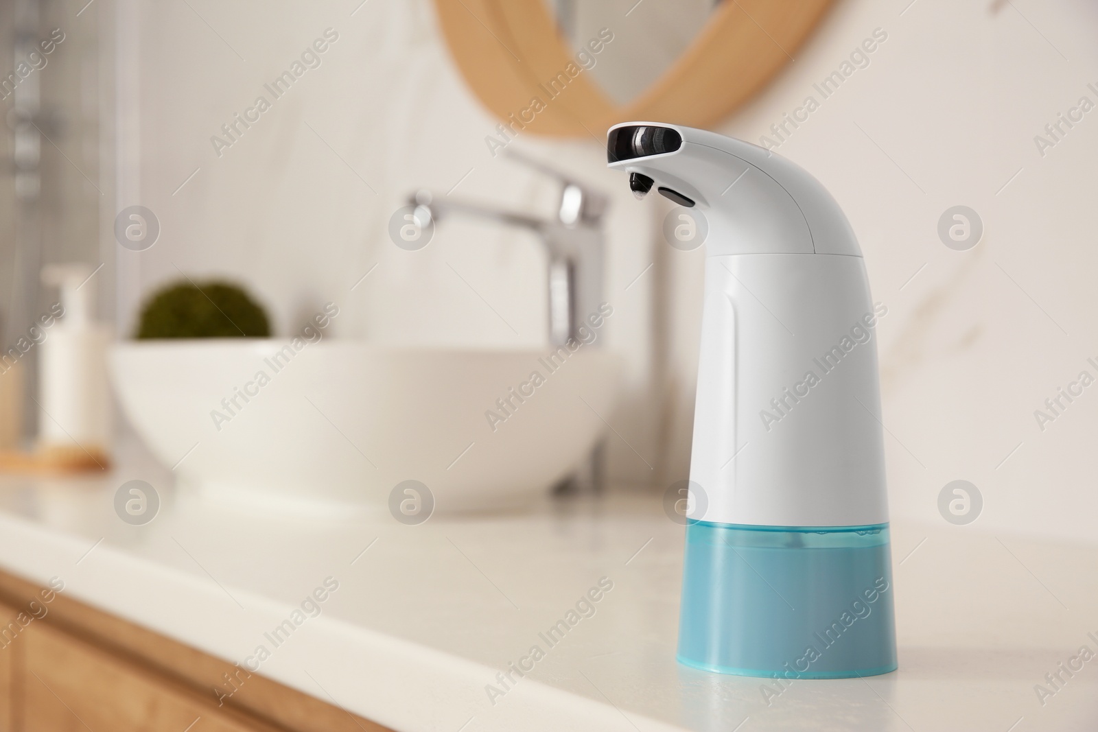 Photo of Modern automatic soap dispenser on countertop in bathroom. Space for text