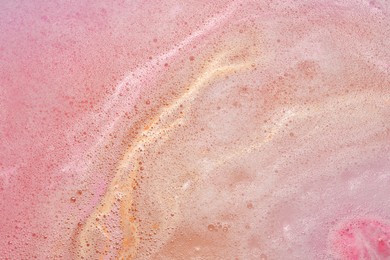 Photo of Colorful foam after dissolving bath bomb in water, closeup