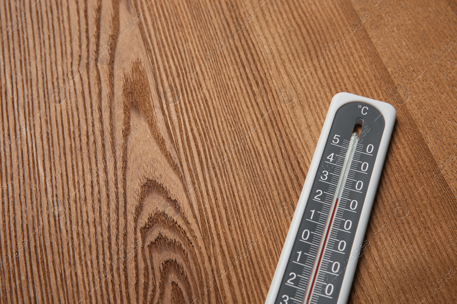 Photo of Weather thermometer on wooden table, closeup. Space for text