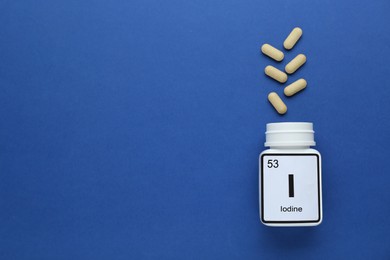 Photo of Plastic jar and iodine pills on blue background, flat lay. Space for text