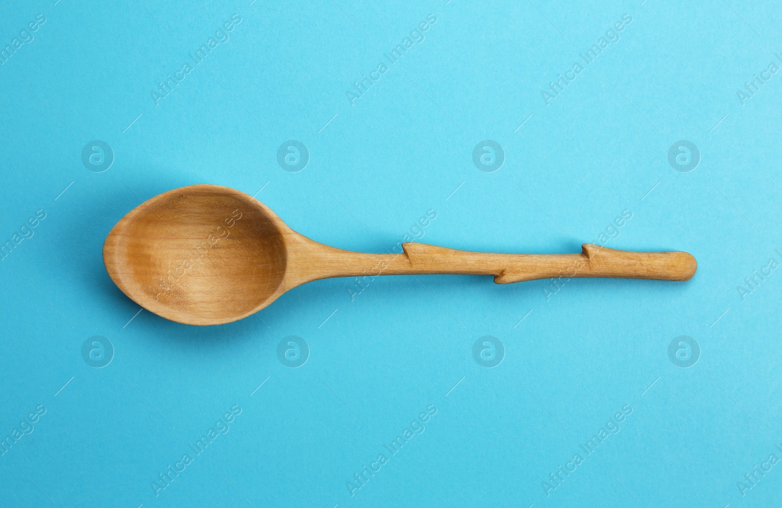 Photo of Clean empty wooden spoon on blue background, top view