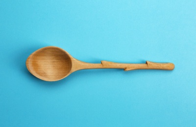 Clean empty wooden spoon on blue background, top view